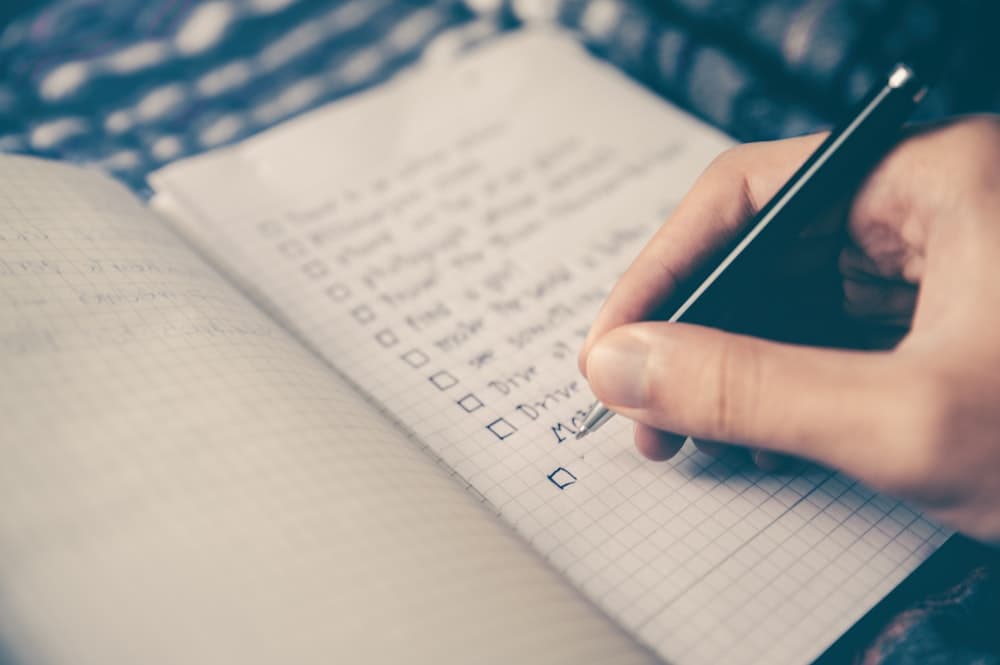 Clean desk workstation with checklist notepad, pen, and laptop for online interview prep